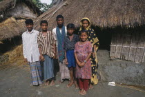 Family standing outside thatched hut.Asia Asian Bangladeshi Kids Asia Asian Bangladeshi Kids