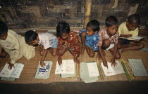 Schoolboys sitting on mats on floor of village school learning to read African Asia Asian Bangladeshi Kids Lessons Teaching African Asia Asian Bangladeshi Kids Lessons Teaching