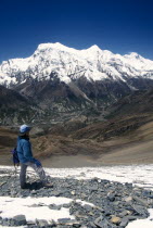 Guide below the Kang La looking towards snow covered peaks of the Annapurnas.trekking trek Asia Asian Nepalese One individual Solo Lone Solitary Scenic 1 Destination Destinations Single unitary