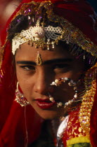 Head and shoulders portrait of young  female dancer wearing red and gold sari and traditional jewellery before the start of the Camel Festival.Asia Asian Bharat Classic Classical Historical Immature...