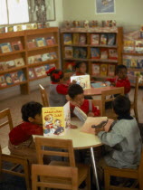 Kindergarten class with children sitting around tables reading books Boys and Girls al Kuwayt Kids Kuwaiti Learning Lessons Middle East Teaching
