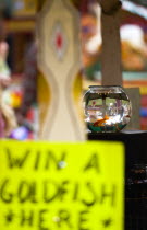 Findon village Sheep Fair Goldfish bowl on a fairground stall with a sign reading Win A Goldfish Here and people in the background inverted in the glass bowl.Great Britain Northern Europe UK United K...