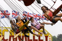Findon village Sheep Fair Four children in motion riding on a swing carousel.Great Britain Northern Europe UK United Kingdom British Isles European