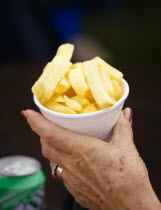 Findon village Sheep Fair Elderly lady holding a polystyrene mug full of potato fries in one hand.Great Britain Northern Europe UK United Kingdom British Isles European