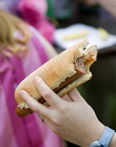 Findon village Sheep Fair Teenage girl holding a hot dog with tomato ketchup and onions with a bite taken out of it.Great Britain Northern Europe UK United Kingdom British Isles European