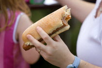 Findon village Sheep Fair Teenage girl holding a hot dog with tomato ketchup and onions with a bite taken out of it.Great Britain Northern Europe UK United Kingdom British Isles European