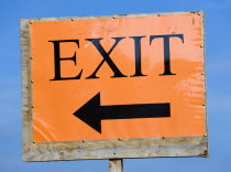 An orange sign with black writing that reads Exit and has an arrow pointing the way out.Great Britain Northern Europe UK United Kingdom British Isles European