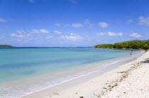 Woman with toddler at the waters edge with gentle waves breaking on Paradise Beach at LEsterre Bay with the turqoise sea and Point Cistern beyond.Beaches Resort Sand Sandy Scenic Seaside Shore Touris...