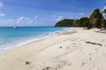 South Glossy Beach in Glossy bay with waves from the turqoise sea breaking on the shore and a yacht at anchor in the bay.Beaches Caribbean Destination Destinations Resort Sand Sandy Scenic Seaside Sh...