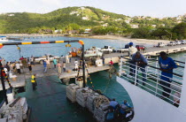 Charlestown Bay Inter island ferry at jetty with people walking amongst trucks with cargo unloaded from boat.Beaches Caribbean Destination Destinations Resort Sand Sandy Scenic Seaside Shore Tourism...