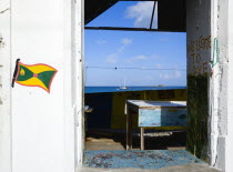 Hillsborough Derelict building in the main street with the Grenadian flag and Welcome To Love painted on the walls with a yacht at anchor in the harbour beyond the ruined building.Beaches Caribbean D...