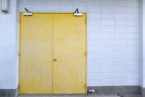 Closed metal yellow doors set in a white wall in Clifton.Caribbean West Indies Windward Islands Destination Destinations Ecology Entorno Environmental Environnement Green Issues