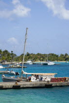 Inter island supply boat unloading provisions onto the main jetty in Clifton with yachts behind moored by the Anchorage Yacht Club in Clifton Harbour.Caribbean West Indies Windward Islands Destinatio...