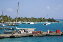 Inter island supply boat unloading provisions onto the main jetty in Clifton with yachts behind moored by the Anchorage Yacht Club in Clifton Harbour.Caribbean West Indies Windward Islands Destinatio...