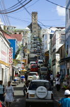 St Juille Street with overhead power cables busy with traffic and pedestrian shoppers leading to the hurricane damaged and roofless Roman Catholic Cathedral in the capital.Caribbean Destination Desti...