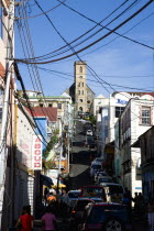 St Juille Street with overhead poer cables busy with traffic and pedestrian shoppers leading to the hurricane damaged and roofless Roman Catholic Cathedral in the capital.Caribbean Destination Destin...