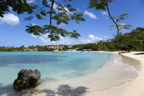 Gentle waves on BBC Beach in Morne Rouge Bay with tourists in the sea on the beach and aboard their tour catamaran in the aquamarine water.Caribbean Destination Destinations Grenadian Greneda West In...