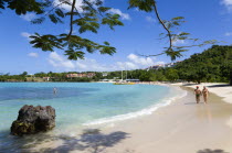 Gentle waves on BBC Beach in Morne Rouge Bay with tourists in the sea on the beach and aboard their tour catamaran in the aquamarine water.Caribbean Destination Destinations Grenadian Greneda West In...