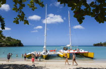 Tourists from cruise ships on BBC Beach in Morne Rouge Bay in the aquamarine sea on the beach and beside their day trip catamarans at the waters edge.Caribbean Destination Destinations Grenadian Gren...