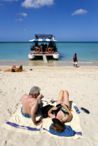 Tourists from cruise ships on BBC Beach in Morne Rouge Bay in the aquamarine sea and on the beach sunbathing beside their day trip catamaran the Rhum Runner.Caribbean Destination Destinations Grenadi...