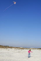 Young girl flying kite on the beachAmerican childrenchildkidkidsplayplayingplayfulchildhoodyoungyouthgirlgirlsyoungschoolageelementarybeachoceanseasandkitepinkjoyjoyousfunhapp...