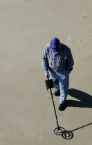 Man using a metal detector on the beach.American manmenmalepeoplepersonadulthumansandbeachoceanseacoastcoastalcoastlinehealthhealthywellnesslifestyleexerciseexercisingsoulfulalo...