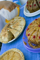 Hand is pointing with the index finger at one of the cakes that are for sale on a table with blue tablecloth.FoodEnergyRecipeSweetTasteCookCuisineEthnicChocolateCherriesNutritionDietCalor...