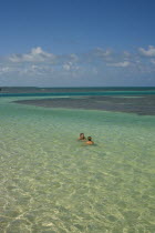 Two women are swimming at an exotic crystal clear green blue sea on a bright sunny day with blue sky and white clouds.2 American Belizean Central America Female Woman Girl Lady Immature Salt Water Wa...