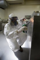 Man wearing protective working uniform and mask while disinfecting and cleaning the interiors of an industrial space.DangerAlertSterilizedCleaningInfectionPollutionEpidemicPandemicDisinfectio...