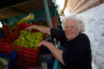 Petrokerasa. Greek old village woman with white hair dressed in black is buying green peppers from a costermonger.TradeCommunityRovingRoamingVagabondFace portraitElderlyThird AgeVillage peopl...