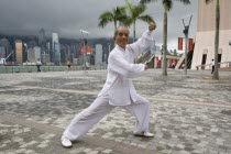 Tsim Sha Tsui  Avenue of the Stars. Portrait of Tai Chi master Mr. Ng at a shadow boxing posture shoot at the Avenue of Stars with Hong Kongs skyscrapers noticeable at the background.Martial artsKun...