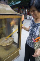 Wong Tai Sin  Sik Sik Yuen Wong Tai Temple. TEMPLE. Chinese woman is lighting a candle as an offering outside of Sik Sik Yuen Wong Tai Sin temple.HistoryVacationHolidaysTravelReligionStructureE...