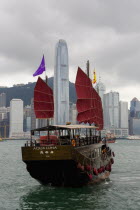Authentic Chinese sailing junk with bat styled boat sails sailing at Victoria harbor with Hong Kong skyscrapers at the background.OldRomanticHistoryTraditionCultureClassicDesignRestorationCon...