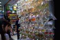 Mong Kok  Tung Choi Street. Two Chinese girls are looking at tropical fishes that Chinese use for Fang Sui improvement  in small plastic water bags with Chinese ideograms and Hong Kong Dollar prices w...