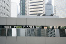 People walking on a futuristic closed top footbridge that connects Hong Kongs skyscrapers  surrounded by tall building.ArchitectureFutureModernTraditionCultureDesignContemporarySkylineSkyscra...