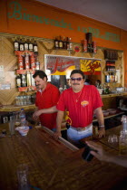 Valladolid / Calle 37. Barman behind bar at a traditional Mexican saloon is posing with style wearing sunglasses while another barman behind him is working.VacationHolidaysTravelExoticFolkloreCu...