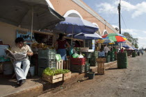 View of the citys main market exteriors with a salesman reading newspaper  colorful umbrellas  fruits  vegetables and customers  shoot on a bright sunny day.FoodTradeCultureTraditionNutritionEth...