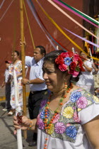 Plaza Principal. Mexican womans portrait wearing Yucatan areas traditional white dress with flowers and holding a candle while participating at a local religious fiesta together with other people.Rel...