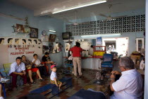 Traditional barber shop with old decorations and customers waiting to be served. Man working on sewing machine in the foreground.TraditionOld fashionCultureFolkloreDecorationHotHeatSummerHoli...