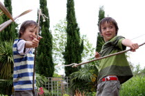 Twin boys playing with bow and arrows made from tree branches and stringUKEnglandFamilyBrothersTwinTwinsPlayingPlayGamesFunMal British Isles European Great Britain Immature Kids Northern Eu...