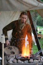 A Saxon using bellows to light a fire.Norman Anglo bellows blowers sparks Saxon fire charcoal flames man hot alight medieval heating reenactment Battle of Hastings 11th century eleventh historical Eu...
