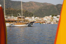 Gulet tourist short cruise boats part framed by orange and yellow parasols on beachfront.Turkish coastMediterraneanHalicarnassusHerodotusMausolusSeven wondersSummerseasonsunsunshinewaterse...