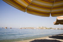 View across bay towards gulf of Gokova with yachts and Gulet boats from beach and line of sun parasols. Turkish Aegean coastmediterraneanresortformerly HalicarnassusHalikarnasregion of CariaDor...