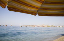 View across bay towards gulf of Gokova with yachts and Gulet boats from beach and sun parasols. Turkish Aegean coastmediterraneanresortformerly HalicarnassusHalikarnasregion of CariaDorian Gree...