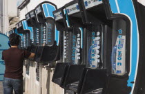 Young Turkish man at row of Turk Telekom public pay telephones in late afternoon summer sun.Turkish Aegean coastmediterraneanresortformerly HalicarnassusHalikarnasregion of CariaDorian Greek oc...