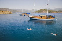 Gulet pleasure boat moored off Gemiler or St Nicholas Island with tourists swimming in perfect clear water in early summer holiday season.Fethiyeformerly Telmessosformerly modern Greek MakriAegean...