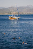 Gulet pleasure boat moored off Gemiler or St Nicholas Island with tourists swimming in perfect clear water in early summer season.Fethiyeformerly Telmessosformerly modern Greek MakriAegeanTurkish...