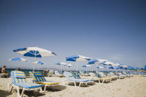 Tingaki beach on North East coast facing Turkey and Bodrum area from shade of blue and white parasol and sunbed with clear bathing beach and water.Greek Islands Tingaki Resort Summer Clear Blue Sky e...