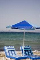 Tingaki beach on North East coast facing Turkey and Bodrum area from shade of blue and white parasol and sunbed with clear bathing beach and waterGreek Islands Tingaki Resort Summer Clear Blue Sky ea...