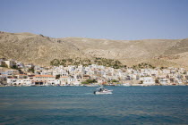 Town seen from the sea  with motorboat passing in the foreground.Greek IslandsResort Summer Clear Blue Sky early season Aegean DodecaneseDestination Destinations Ellada European Greek Southern Europ...